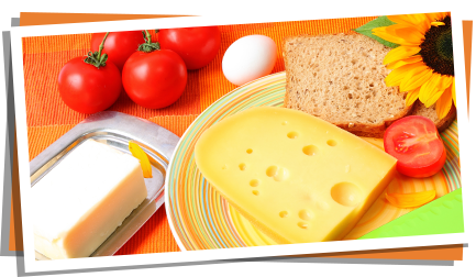 Ein Teller mit Brot und Käse, daneben Butter, ein Ei und Tomaten